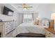 A spacious main bedroom featuring a tray ceiling, large window and decorative furniture with a television at 2040 Water Marsh Trl, Fuquay Varina, NC 27526