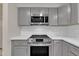 Close-up view of stainless oven, microwave, and gray cabinets with subway tile backsplash at 215 Longview Dr, Smithfield, NC 27577