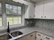Well-lit kitchen featuring a double sink, granite countertops, and white cabinets at 2616 Firelight Rd, Raleigh, NC 27610