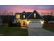 Beautiful two-story home with warm exterior lights illuminating the yard and driveway at dusk at 36 Deep Woods Ln, Cameron, NC 28326