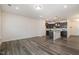 Open-concept living space with modern gray wood floors and an adjacent kitchen featuring dark cabinetry and an island at 4220 Congleton Pl, Durham, NC 27703