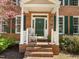 Charming front porch with green door and shutters, brick stairs, white columns, and rocking chair at 5125 Salinas Ct, Holly Springs, NC 27540