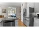 Modern kitchen with stainless steel refrigerator, granite counters, white cabinetry, and view to living area at 5125 Salinas Ct, Holly Springs, NC 27540