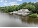 Picturesque view of lake house on water with lush trees surrounding it at 5125 Salinas Ct, Holly Springs, NC 27540
