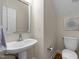 Simple powder room with a pedestal sink, mirror, and toilet at 5125 Salinas Ct, Holly Springs, NC 27540