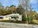 View of a home surrounded by trees and foliage, featuring light grey siding and red shutters at 5324 Rock Quarry Rd, Raleigh, NC 27610