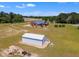 Aerial shot of a property featuring a brick house, a shed, and a spacious lawn with surrounding trees at 5595 Godwin Lake Rd, Benson, NC 27504