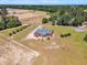 Aerial view of the brick home with large lawn, long driveway, and a view of surrounding fields and woods at 5595 Godwin Lake Rd, Benson, NC 27504