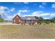 Brick home with a screened porch and well-maintained landscaping, set on a large lawn under a blue sky at 5595 Godwin Lake Rd, Benson, NC 27504