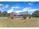 Beautiful brick home featuring a screened porch, a garden area, and a green lawn on a sunny day at 5595 Godwin Lake Rd, Benson, NC 27504