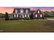 Well-maintained home featuring a manicured lawn, mature trees, and a classic brick facade at dusk at 5595 Godwin Lake Rd, Benson, NC 27504