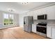 Bright kitchen with stainless steel appliances, white cabinetry, and hardwood floors at 5745 Spence Farm Rd, Holly Springs, NC 27540