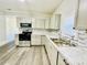 Kitchen featuring white cabinets, modern appliances, and updated floors and backsplash at 602 Dexter St, Rocky Mount, NC 27803