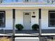Inviting front porch featuring a gray front door, decorative plants and sleek black pillars at 602 Dexter St, Rocky Mount, NC 27803
