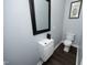 Modern powder room featuring a sleek vanity, black framed mirror and warm wood-look flooring at 6521 Vintage Ridge Ln, Fuquay Varina, NC 27526