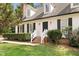 Close up of brick steps and a black front door with white siding, black shutters, and manicured landscaping at 7616 Valley Run Dr, Raleigh, NC 27615