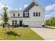 Charming two-story home with blue and white color scheme, a well-manicured lawn, and attached garage at 779 Old Station Pointe, Angier, NC 27501