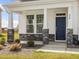 Inviting covered front porch with stone pillar bases and a stylish dark blue front door at 779 Old Station Pointe, Angier, NC 27501