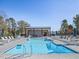 Community pool with lounge chairs, tables, umbrellas, and pool house under a clear blue sky at 779 Old Station Pointe, Angier, NC 27501