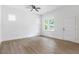 Bright, minimalist bedroom featuring hardwood floors, white walls, a ceiling fan, and natural light from windows at 812 East St, Smithfield, NC 27577