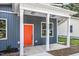 Close-up of a home's covered front porch with white columns, a vibrant orange door, and dark blue siding at 812 East St, Smithfield, NC 27577