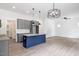 Open-concept living and kitchen area with wood floors, gray cabinets, a blue island, and modern lighting fixtures at 812 East St, Smithfield, NC 27577