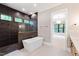 A modern bathroom featuring a standalone tub, dark tiled shower, and elegant finishes throughout at 92 Bluffside Ct, Pittsboro, NC 27312