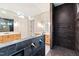 A sleek, modern bathroom with double vanities, dark-tiled shower and elegant gold fixtures at 92 Bluffside Ct, Pittsboro, NC 27312