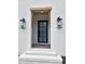 Inviting front door with wood beam detail and glass lanterns on a white brick facade at 92 Bluffside Ct, Pittsboro, NC 27312