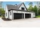Three-car garage with modern black doors, exterior lighting, and well-maintained landscaping at 92 Bluffside Ct, Pittsboro, NC 27312