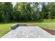 Paver patio with retaining wall overlooking the landscaped backyard and surrounding woods at 92 Bluffside Ct, Pittsboro, NC 27312