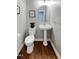 Charming powder room with pedestal sink, decorative mirror and dark wood floors at 101 Goldenthal Ct, Cary, NC 27519