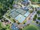 Aerial view of tennis courts, parking, and a clubhouse surrounded by lush greenery at 1023 Kelton Cottage Way, Morrisville, NC 27560