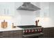 Close up of range with white subway tile backsplash, stainless steel hood, and white cabinets at 110 N Corcoran St # 2502, Durham, NC 27701