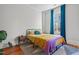 Cozy bedroom featuring hardwood floors, a comfortable bed, and bright blue curtains at 1310 S 8Th St, Lillington, NC 27546