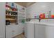 Bright laundry room with white shiplap walls, built-in storage, and side-by-side washer and dryer at 1310 S 8Th St, Lillington, NC 27546