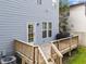 View of the home's back exterior and wooden deck with stairs and grill at 1515 E Jones St, Raleigh, NC 27610