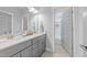 Bathroom with double sinks, gray cabinets, and a view of the tiled shower/tub through the doorway at 1515 E Jones St, Raleigh, NC 27610