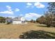 Large backyard showing a white two-story home with an enclosed porch, garage and expansive lawn at 153 Glenn Oak Dr, Sanford, NC 27332