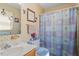 Well lit bathroom features vintage floral wallpaper, shower and tub with curtain, and single sink at 153 Glenn Oak Dr, Sanford, NC 27332