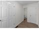 Hallway leading to bathroom with multiple white doors and wood style flooring at 202 Wimbledon Ct, Clayton, NC 27520