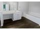 Bright bathroom features dark wood floors, sleek white vanity, and bathtub at 2053 Alderman Way, Creedmoor, NC 27522