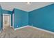 Blue-walled bedroom with carpeted floors and adjacent hallway showcasing additional rooms at 215 Mystic Pine Pl, Apex, NC 27539