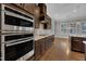 Modern kitchen with stainless steel oven and microwave combo, cooktop, tile backsplash, and sleek dark wood cabinetry at 215 Mystic Pine Pl, Apex, NC 27539