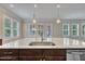 Bright kitchen with large island, stainless steel sink, granite countertops, and natural light pouring through windows at 215 Mystic Pine Pl, Apex, NC 27539