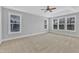 Bright primary bedroom with large windows, tray ceiling with fan, and neutral carpet at 215 Mystic Pine Pl, Apex, NC 27539