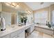 A bright bathroom features a tub with tile surround, a shower, and a dual sink vanity at 2308 Carriage Oaks Dr, Raleigh, NC 27614