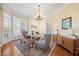 Bright dining area featuring a modern chandelier, large windows, and a wooden accent table at 2308 Carriage Oaks Dr, Raleigh, NC 27614