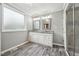 Well-lit bathroom with double vanity, granite countertops, wood-style flooring, and a glass-enclosed shower at 327F Bobbitt Rd, Clayton, NC 27520
