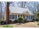 Exterior view of a well-maintained home with vinyl siding, a brick chimney, and mature trees at 401 Joyce Rd, Hillsborough, NC 27278